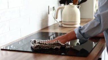Modern cam seramik elektrik yüzeyini sünger ve deterjanla temizleyen kadın eli. Temizlik indüksiyon sobası. Kadın mutfak indüksiyon hobisini havluyla temizliyor..