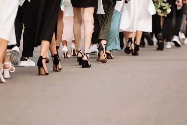 the feet of the group of people are walking outdoors. graduation day. stylish young guys and girls in stylish shoes