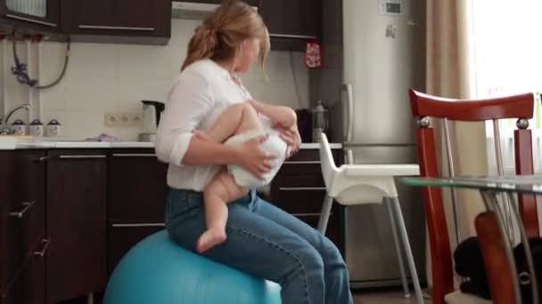 Uma Jovem Mãe Balança Seu Bebê Uma Bola Fitness Menina — Vídeo de Stock