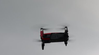 Hovering drone flying upward on a cloudy sky backdrop. copter flying