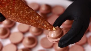 Şefin ellerinin çikolatalı badem kabuğuna fındıklı tuzlu karamelli ganache kreması koyması. Makarna Fırını Konsepti. Pişirme, Yemek ve Pişirme Konsepti. Şekerleme ve Pişirme Konsepti