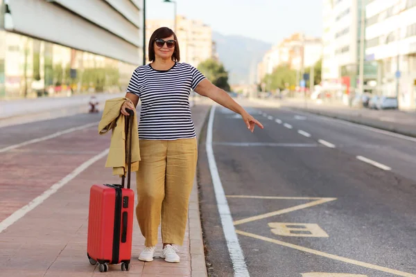 Smiling Senior Business Woman Sunglasses Red Suitcase Raising Hand Catch — Stockfoto