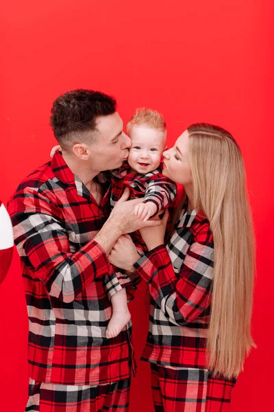 Smiling Young Mother Father Kissing Hugging Baby Boy Red Background — Stock fotografie