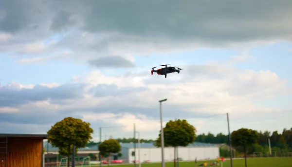 Hovering drone flying upward on a cloudy sky backdrop. copter flying
