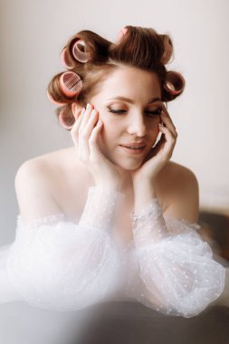 Güzellik konsepti Pembe bukleli parlak makyajlı, gösterişli, genç bir esmer kadının portresi. Stüdyo Çekimi, Kırpılmış. Yüz bakımı. Kozmetoloji, cilt bakımı ve kaplıca.