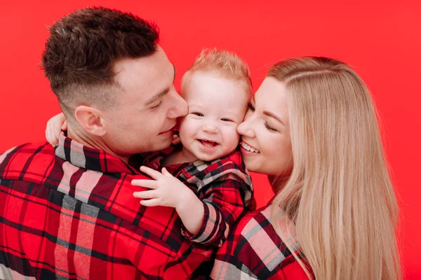 Smiling Young Mother Father Kissing Hugging Baby Boy Red Background — Fotografia de Stock
