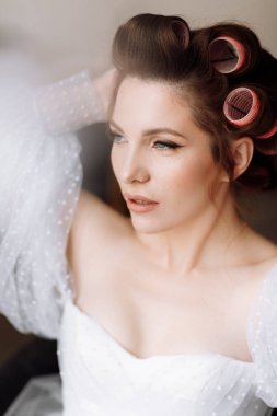 Güzellik konsepti Pembe bukleli parlak makyajlı, gösterişli, genç bir esmer kadının portresi. Stüdyo Çekimi, Kırpılmış. Yüz bakımı. Kozmetoloji, cilt bakımı ve kaplıca.