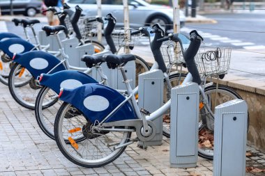 Kiralık E-motorlar, elektrikli motorların desteklediği bisikletler, şehir caddesinde bir rıhtım limanında arka arkaya park edilir. Modern kiralık elektrikli bisikletler şarj sırasında yan yana durur. Avrupa eko kavramı