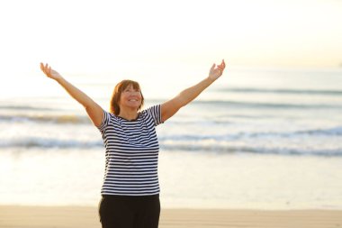 Yoga and meditation of mature woman practicing breath exercises on the sea beach on sunrise in the morning. Body mind and spirit, mindfulness concept. Enlightenment and healthy lifestyle