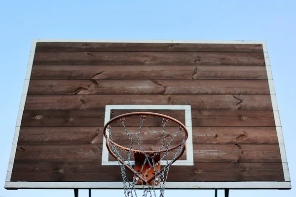 basketball hoop, metal net and wooden backboard for game on blue sky background. Basketball court outdoors. Recreational sport equipment on streetball field alfresco, playground on street