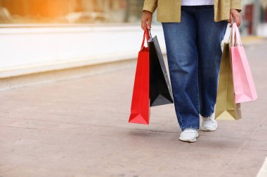 Alışveriş merkezinin arka planında rengarenk alışveriş torbaları olan tanınmayan bir kadın. Satın almalar, kara cuma, indirimler, satış konsepti. Çevrimiçi alışveriş konsepti, mevsimlik satışlar. Boşluğu kopyala.