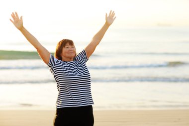 Yoga and meditation of mature woman practicing breath exercises on the sea beach on sunrise in the morning. Body mind and spirit, mindfulness concept. Enlightenment and healthy lifestyle