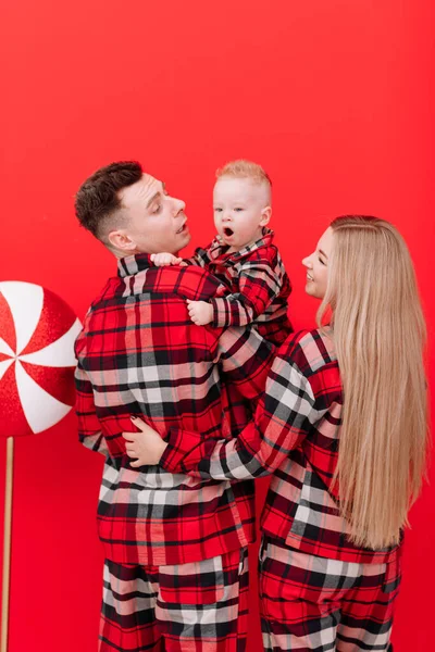 Smiling Young Mother Father Kissing Hugging Baby Boy Red Background — Stock fotografie