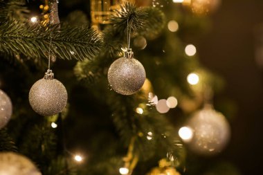 Güzel köknar dallarının parlak altın mücevheri ya da topu, kostüm süsleri ve ışıkları, Noel tatilleri arka planında yakın görünümü. kopyalama alanı. Noel ağacının süslemesi. Yeni Yıl Kutlaması 2023.