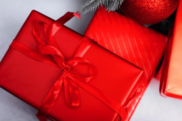 Red gift boxes with ribbons and Christmas baubles on white background. Surprises in boxes wrapped in red gift paper with bow. Concept of holidays and greeting cards