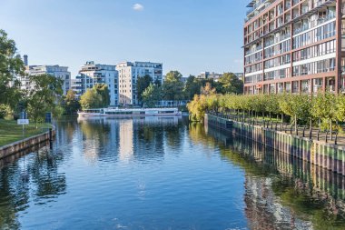 Berlin, Almanya - 7 Ekim 2021: Landwehr Kanalı Salzufer ve Einsteinufer kıyıları modern konut evleri ve Dovebruecke Köprüsü 'nden görülen gezi teknesi Fortuna