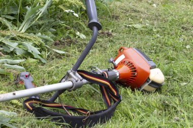 Arka planında benzin motoru olan bahçe budama makinesi..