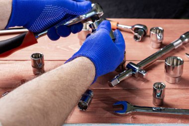 Koruyucu eldivenli bir ustabaşının elleri anahtar, araba ya da motosiklet tamir konseptiyle çalışır.