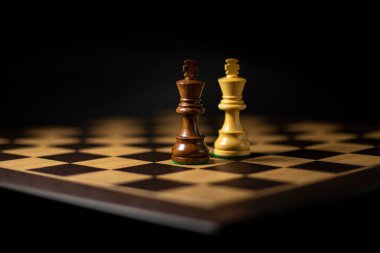 Siyah arka planda kralların figürlerinin olduğu satranç tahtası, rekabet konsepti, seçici odaklanma.