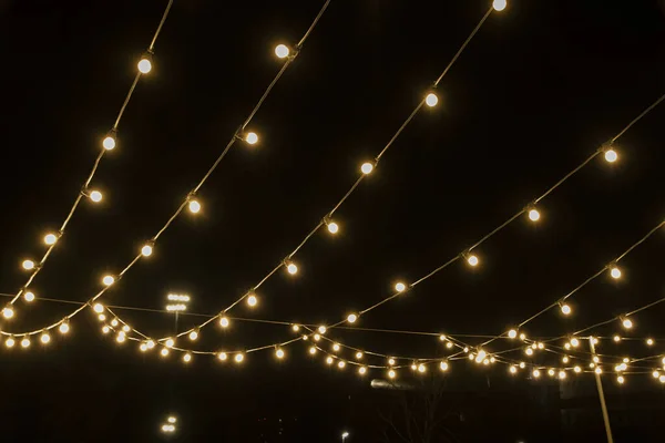 Gece gökyüzünün arka planında parlak çelenkler, sokak fotoğrafının bakış açısı