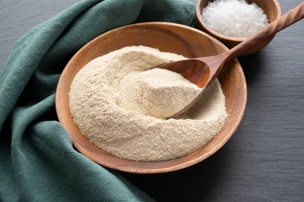 Amaranth flour with a spoon in wooden bowl on black slate background — Foto Stock