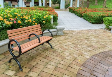 Kamu parkında renkli çiçek arkaplanı olan boş bir koltuk 