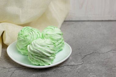 Beyaz fincan tabağında mojito aromalı yeşil lokum ve gri arka plan..