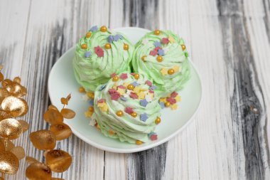 Noel yeşili mojito aromalı marshmallow. Beyaz çay tabağı ve beyaz ahşap arka planda çok renkli şeker parçacıkları serpiştirilmiş. Şenlikli dekore edilmiş Yeni Yıl tatlı yemekleri.