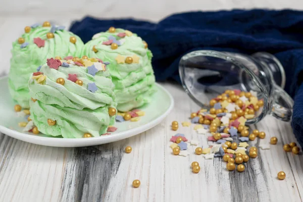 Noel yeşili mojito aromalı marshmallow 'u kapayın. Beyaz çay tabağı ve beyaz ahşap arka planda çok renkli şeker parçacıklarıyla süsleyin..