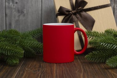 Yazıtlar için kırmızı bardağın bir kopyası. Arka planda hediye kutusu ve bir Noel ağacının dalları var. Bardaklara yazı yazmak için çiziminiz için şenlikli bir model..