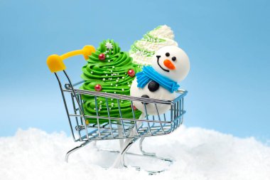 Şekerleme şekeri süslemeleri kar altında bir alışveriş arabasında yatıyor..