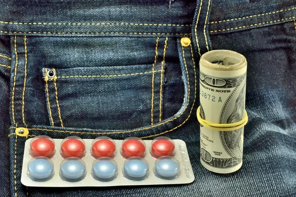Таблетки і долари на джинсах — стокове фото