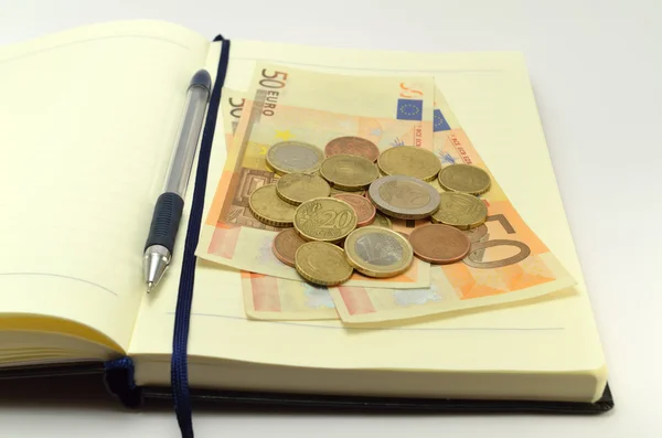 Notebook coins and banknotes — Stock Photo, Image