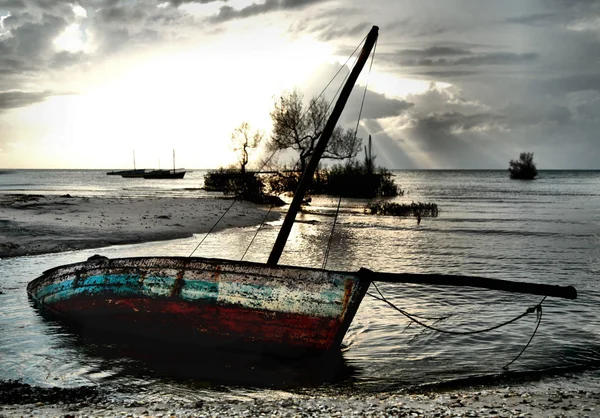 Rosso Bianco Blu Dhow Barca a vela bloccata con bassa marea nell'oceano M — Foto Stock