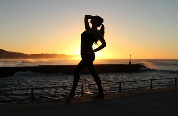 Dancer is dancing on the pier and the rising sun over the ocean — Stock Photo, Image