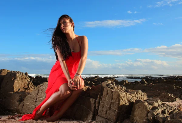 Brunette in red dress on the beach — Stock Photo, Image