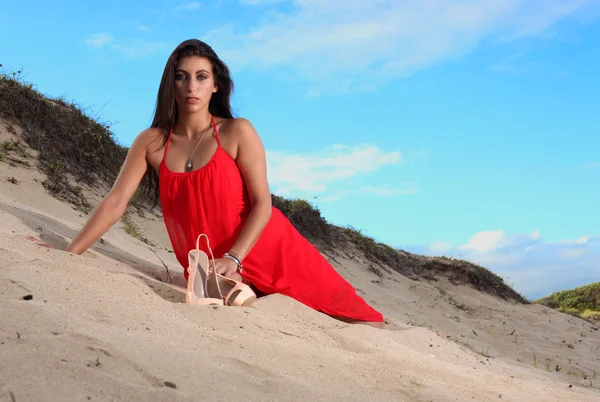 Brunette in red dress resting on the beach — Stock Photo, Image