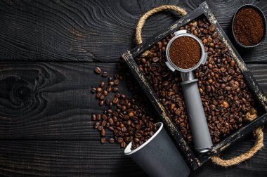 Espresso için Portafilter 'daki Ground Coffee kahve çekirdekli ahşap bir tepside. Siyah ahşap arka plan. Üst Manzara. Boşluğu kopyala