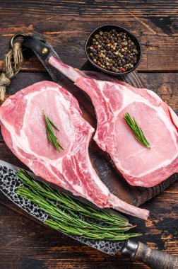 Mermer, çiğ domuz pirzolası, biftek ya da balta. Koyu ahşap arka plan. Üst görünüm