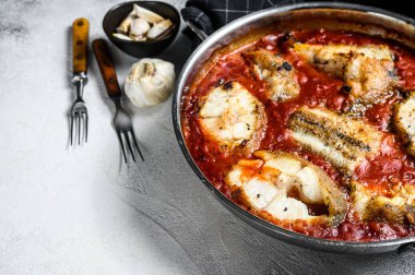 Tavada domatesli haşlanmış beyaz balık. Beyaz tahta arka plan. Üst Manzara. Boşluğu kopyala