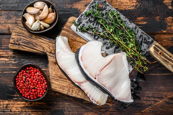 Blue Shark raw fish steaks on a cutting board with cleaver. Dark wooden background. Top view