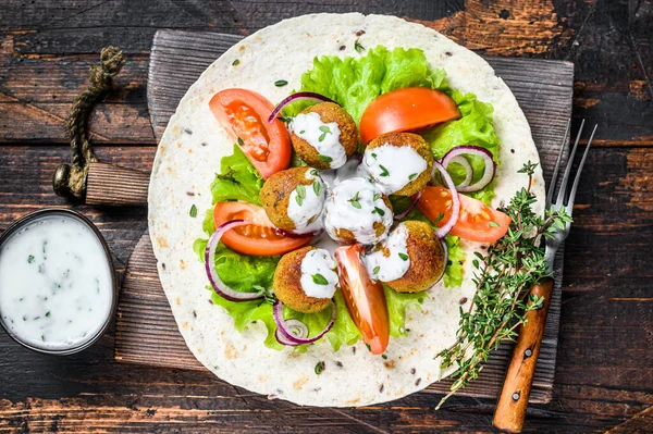 Vegetarische falafel met groenten en tzatziki saus op een tortilla brood. Donker houten achtergrond. Bovenaanzicht — Stockfoto