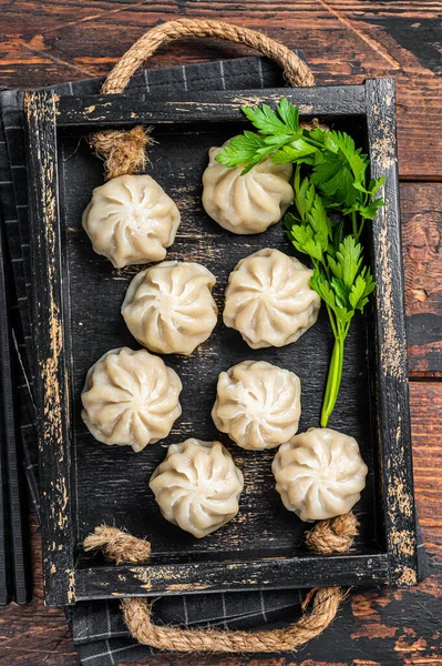 Tahta tepside otlu Momo hamur tatlısı. Karanlık ahşap arka plan. Üst görünüm