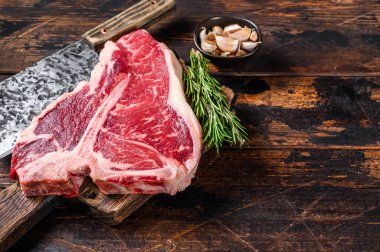 İtalyan Floransa bifteği. Tahta bir kesme tahtasının üzerinde otlu biftek. Koyu ahşap arka plan. Üst Manzara. Boşluğu kopyala