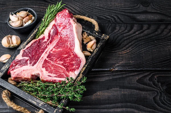 Biftek ya da çiğ biftek, otlu biftek ve ahşap tepside tuz. Siyah ahşap arka plan. Üst Manzara. Boşluğu kopyala