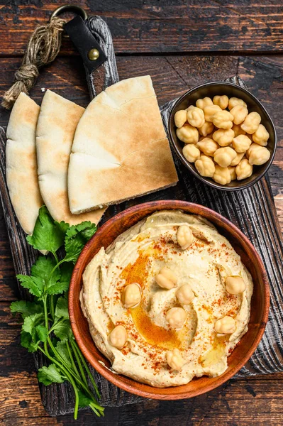 Hummus paste with pita bread, chickpea and parsley in a wooden bowl. Dark wooden background. Top view — Stock Photo, Image