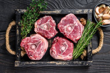 Bıçakla kasap masasında çiğ kuzu eti. Siyah ahşap arka plan. Üst görünüm