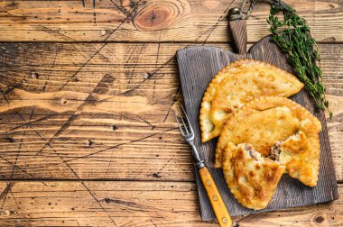 Tahta kesme tahtasının üzerinde servis edilen kıymalı et ile dolu Şili usulü kızarmış börekler. Ahşap arka plan. Üst Manzara. Boşluğu kopyala