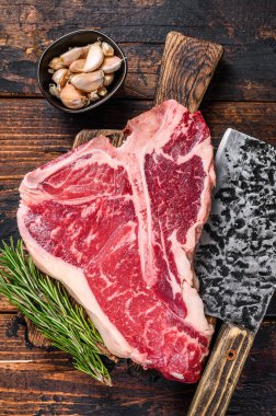 İtalyan Floransa bifteği. Tahta bir kesme tahtasının üzerinde otlu biftek. Koyu ahşap arka plan. Üst görünüm