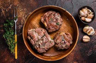 Ahşap bir tabakta kuzu budu bifteği ve otlar. Karanlık arka plan. Üst görünüm